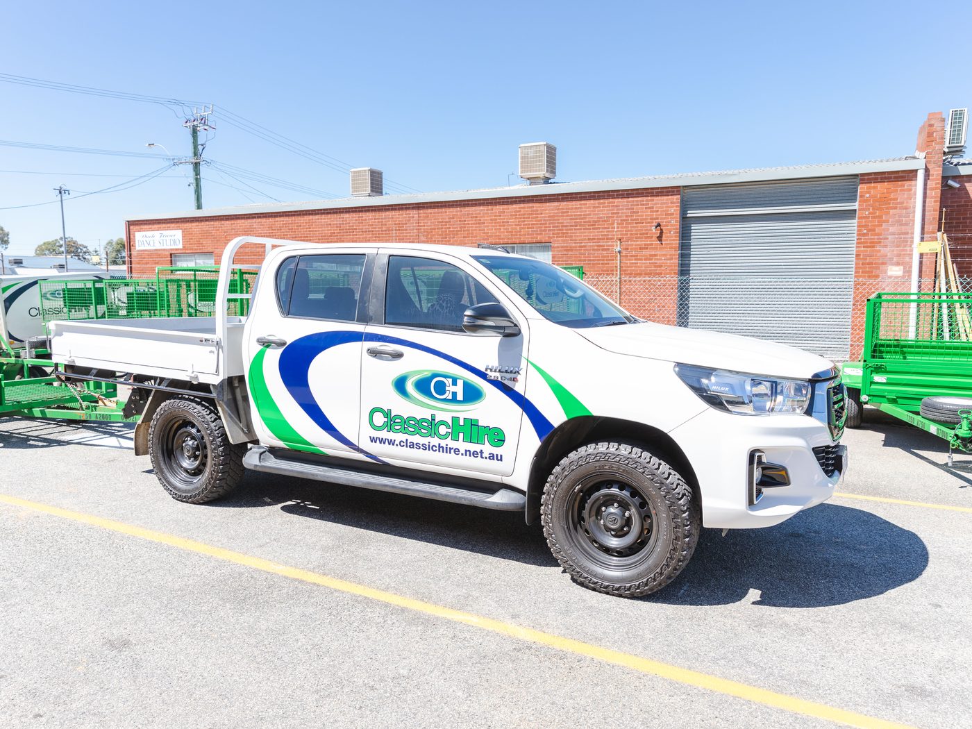 Classic Hire branded ute parked beside green hire trailers in Perth